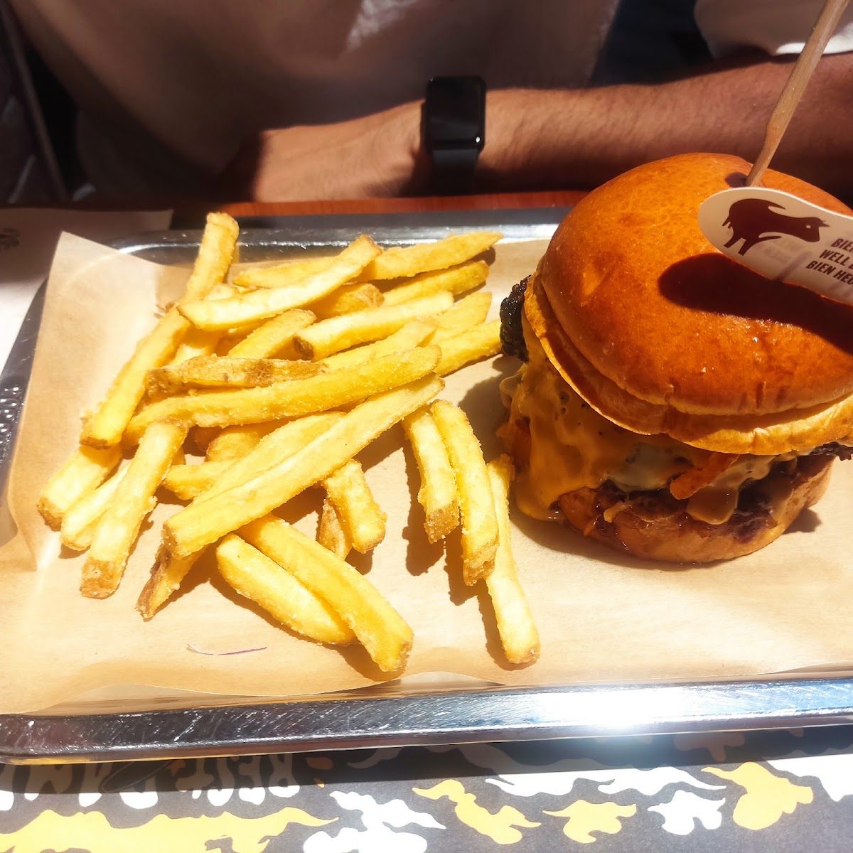 Burger en brioche con patatas fritas en bandeja metálica